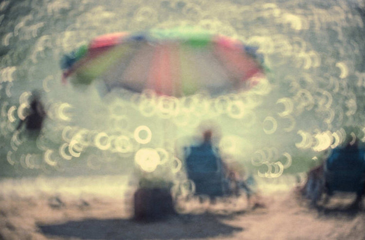 A Man with a Blue Shirt Sitting Under a Pretty Umbrella