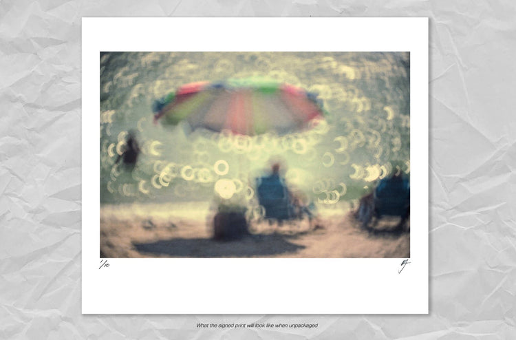 A Man with a Blue Shirt Sitting Under a Pretty Umbrella