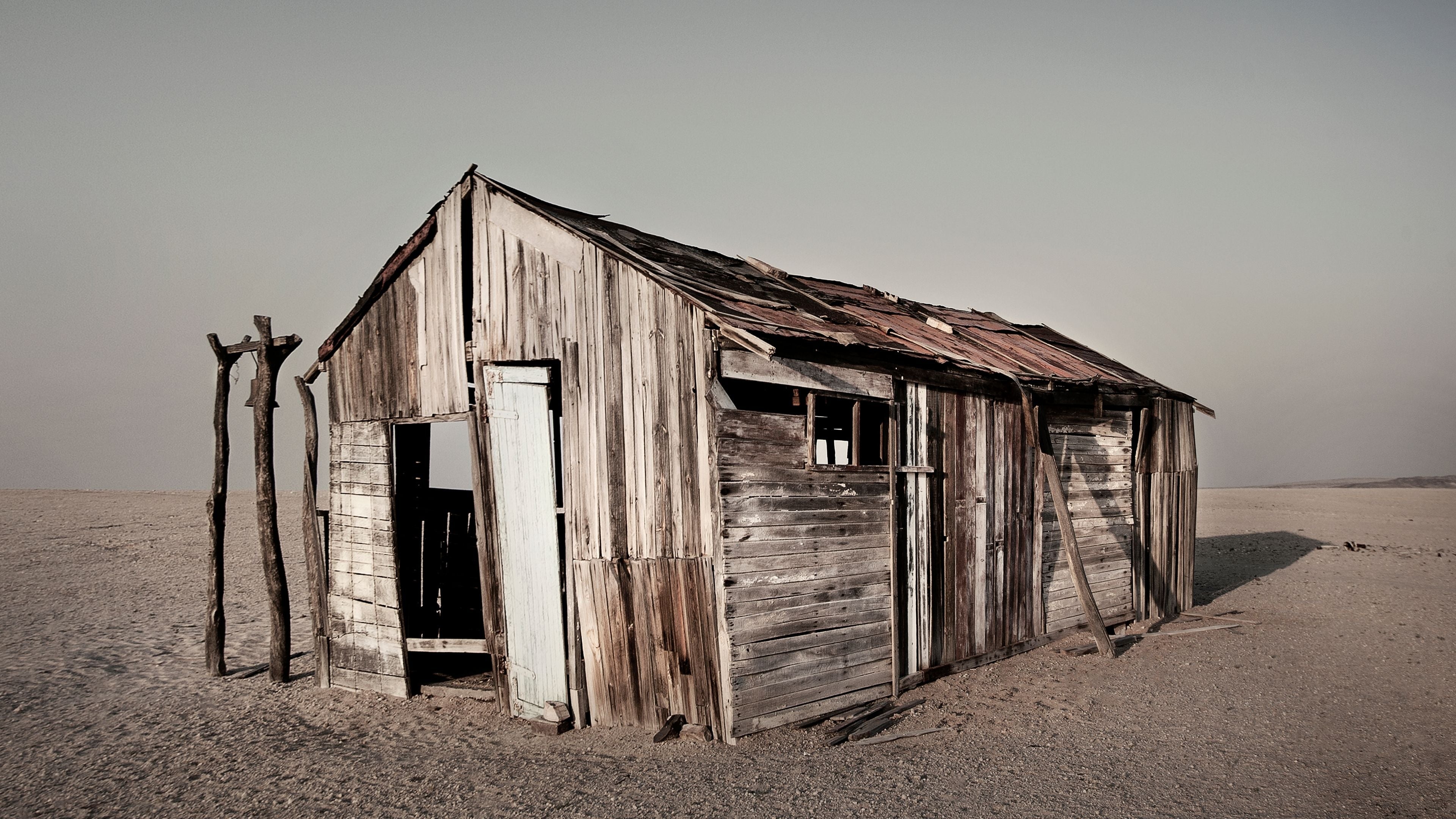 Fine art depiction of an abandoned wooden shack in a barren desert landscape, weathered by time and elements